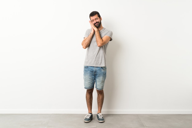 Un long coup de bel homme à la barbe faisant un geste du sommeil dans une expression dorable