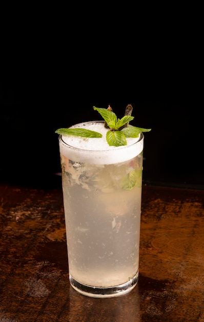 Long drink rafraîchissant avec de la mousse de menthe sur une table en bois sur fond noir vue d'angle