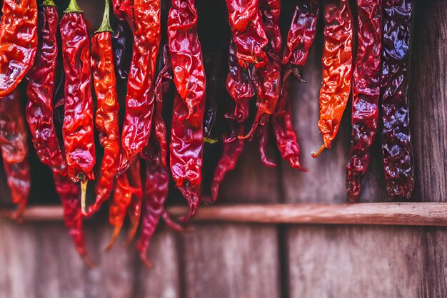 Long poivron rouge séché suspendu à une corde sur fond gris