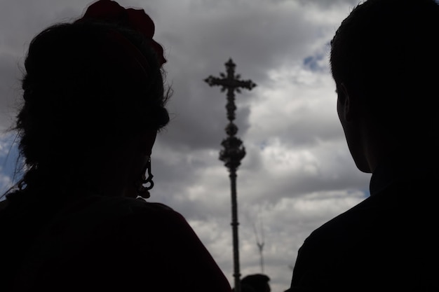 long shot d'un couple rétro-éclairé devant une croix catholique