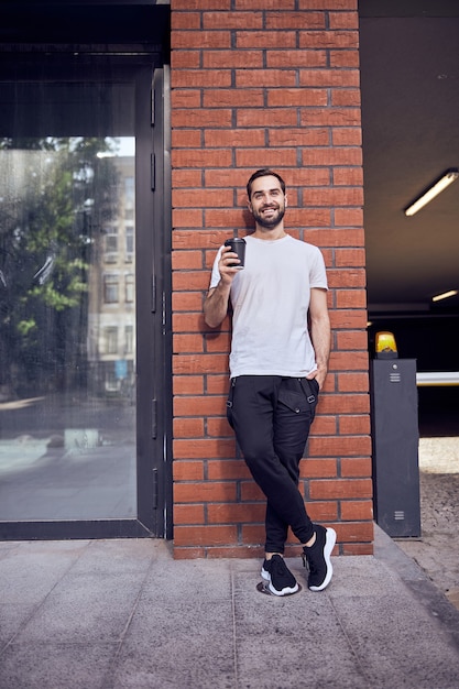 Long up portrait d'un gars heureux debout contre le mur