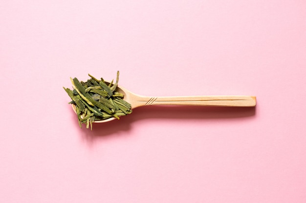 Longjing. Thé Vert Feuille Chinoise Dans Une Cuillère Sur Un Fond Rose.