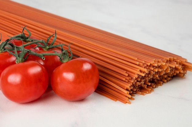 Longs spaghettis rouges et tomates cerises sur fond gris