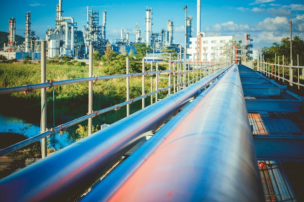 Longs tuyaux en acier dans l'usine de pétrole brut pendant la tour de l'usine de raffinerie de fond coucher de soleil et la colonne de pétrochimie