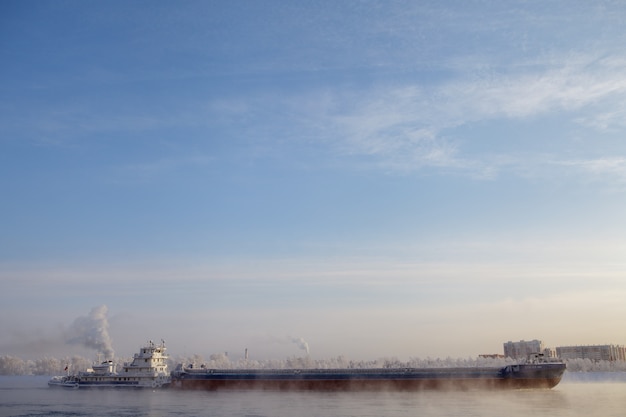 Longue barge descendant la rivière en hiver froid