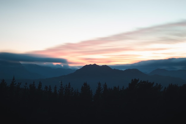 Longue exposition d'un paysage avec des montagnes et des arbres au coucher du soleil