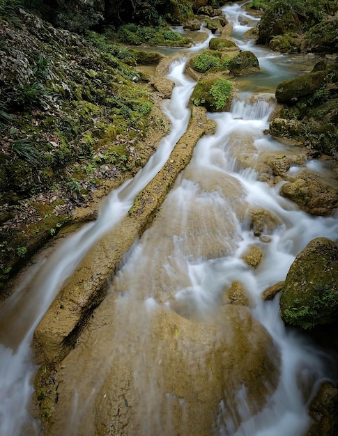 Une longue exposition d'une rivière avec une cascade au milieu.