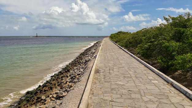 Longue passerelle en pierre à côté de l'océan ondulé sous le ciel bleu nuageux