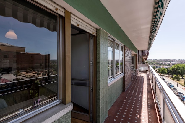 Longue terrasse véranda avec sols en terrazzo et vue sur un parc par une journée ensoleillée