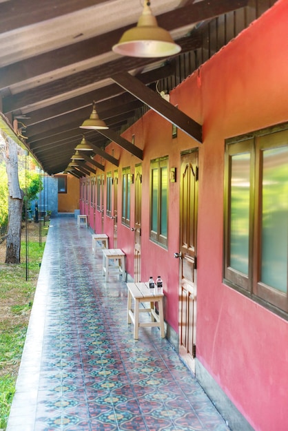 Longue terrasse vide ouverte avec carrelage mural rouge et rangée de fenêtres et portes en bois dans un hôtel asiatique