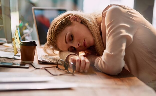 De longues heures font des ravages Photo d'une jeune femme d'affaires épuisée endormie à son bureau dans un bureau