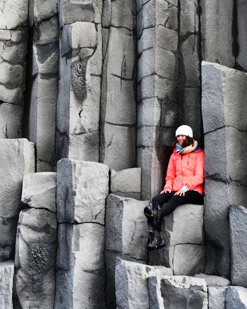 Longueur complète d'une femme assise sur une formation rocheuse