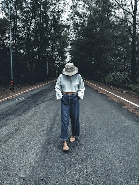 Photo la longueur complète de la femme debout sur la route contre les arbres