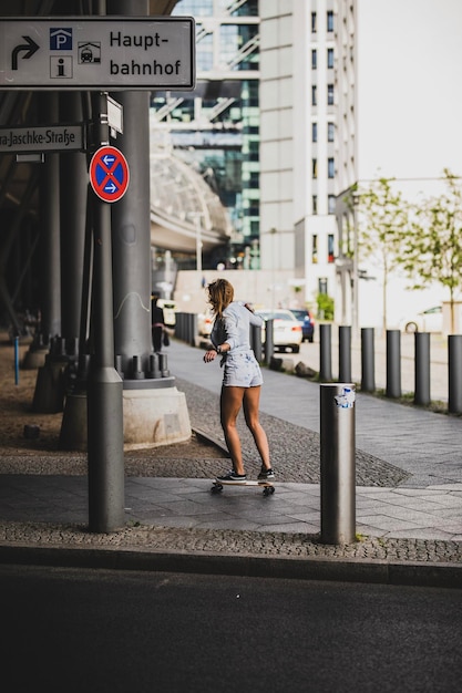 La longueur complète d'une femme faisant du skateboard sur la route