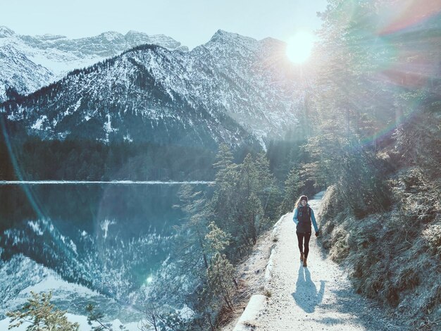 La longueur complète d'une femme marchant sur une route de montagne en hiver