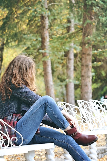 Photo longueur complète de la femme portant une chaussure assise sur un banc