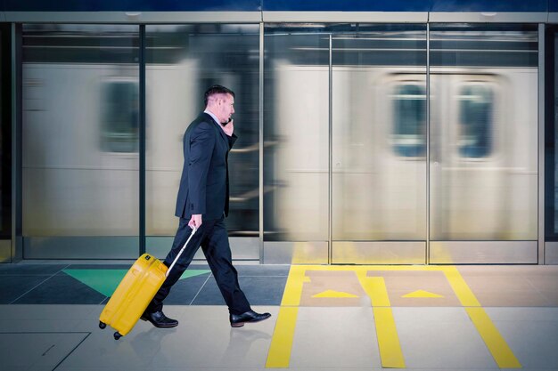 Photo longueur complète d'un homme d'affaires marchant avec des bagages à la gare