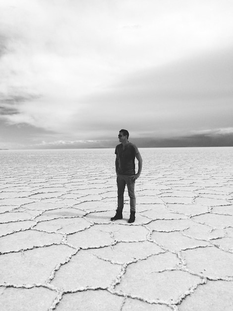 Photo longueur complète de l'homme debout sur le sel plat contre le ciel nuageux
