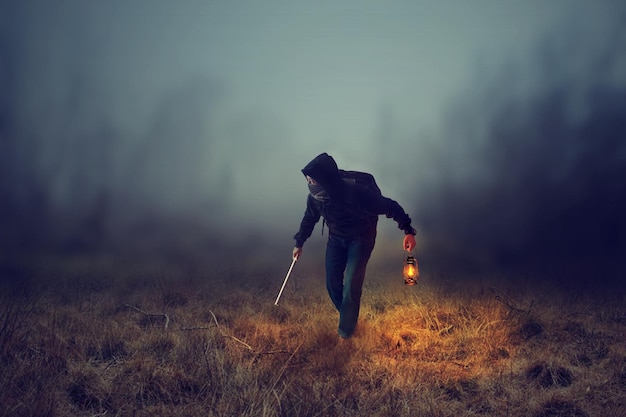Longueur complète de l'homme avec la lanterne debout sur le champ par temps brumeux