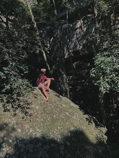 Photo longueur complète de l'homme sur le rocher dans la forêt