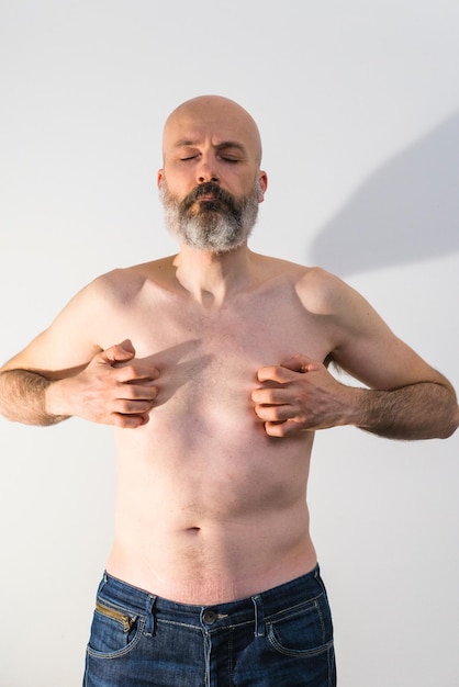 Photo longueur complète d'un homme sans chemise debout sur un fond blanc