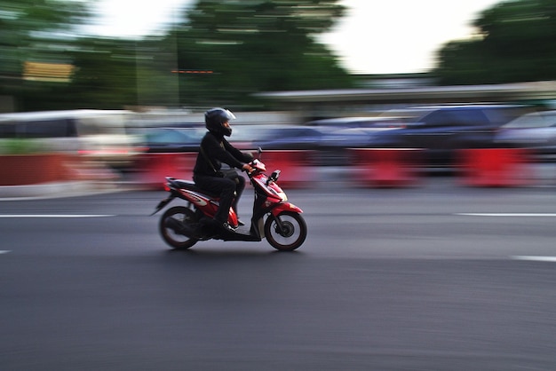 Longueur complète d'un homme sur un scooter à moteur dans la rue