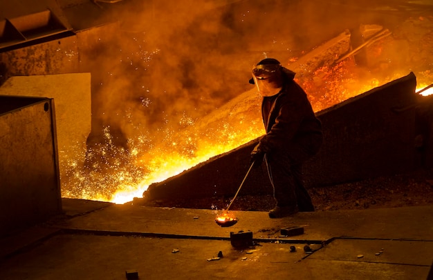 Longueur complète de l'homme travaillant alors qu'il se tient près du feu dans l'usine