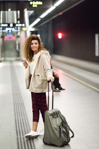 Longueur complète d'une jeune femme avec des bagages debout à la gare