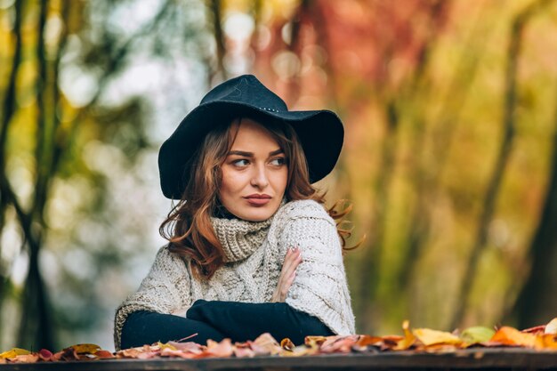 Le look d'une belle dame au chapeau noir est dirigé sur le côté.