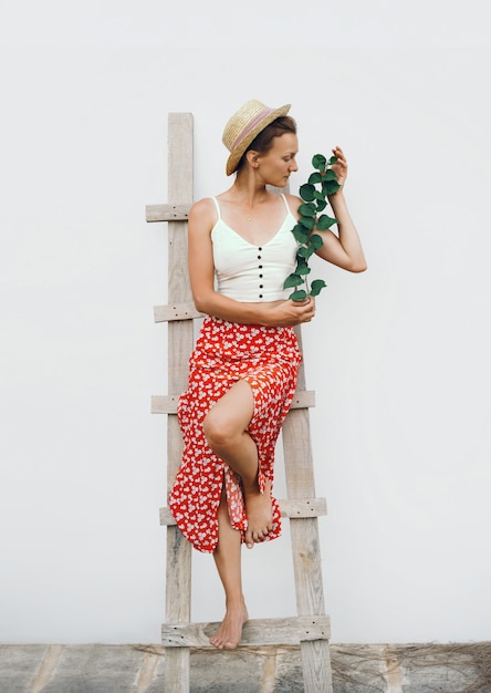 look de mode rustique féminin avec une plante verte style élégant belle jeune femme contre un mur blanc