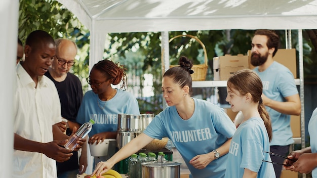 Photo lors d'une collecte de nourriture à but non lucratif, vue latérale de travailleuses caritatives distribuant de la nourriture gratuite aux moins fortunés. des bénévoles amicaux fournissant une aide humanitaire aux personnes pauvres et sans abri. prise de vue sur trépied.