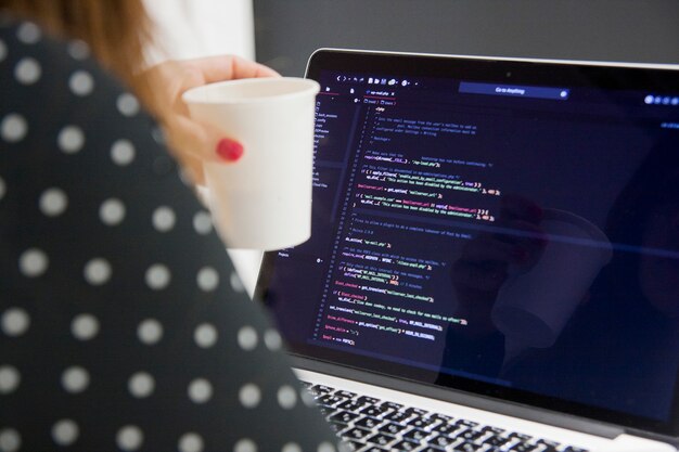 Los Angeles, Californie, USA - 27 décembre 2018: femme programmeur avec une tasse de café travaillant sur un ordinateur portable au bureau