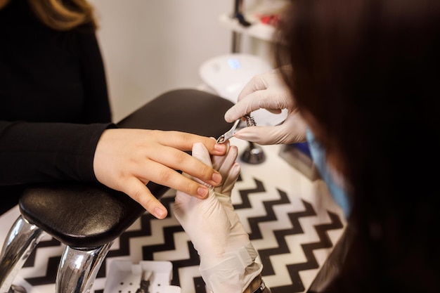 Сlose d'une manucure dans des gants en latex coupant la procédure de manucure bordée de la cuticule du client