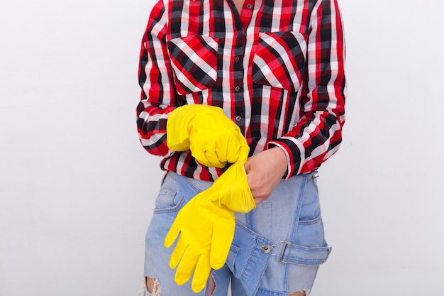 Ã Â¡lose up of young woman in jeans and plaid shirt mains portant des gants de protection en caoutchouc jaune. Travaux ménagers et sécurité des femmes, concept d'entretien ménager
