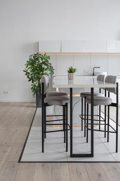 Îlot de cuisine et salle à manger avec tabourets de bar hauts dans un design de luxe moderne minimaliste d'une maison chère par une journée ensoleillée murs blancs avec éclairage décoratif en parquet en plâtre et personne à l'intérieur