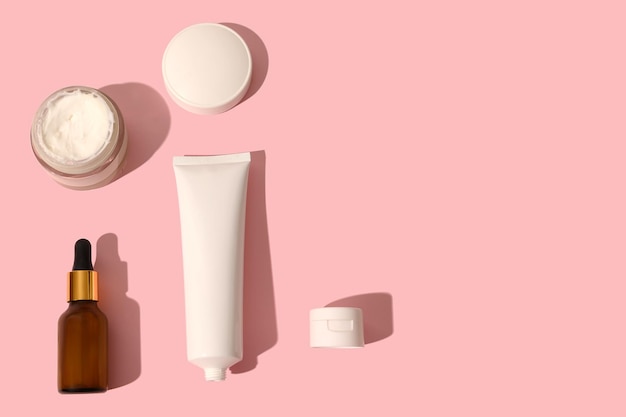 Lotion cosmétique et crème avec ombre noire sur fond rose Place pour le texte