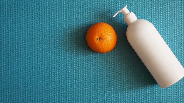 Lotion et fruit orange - concept anti-cellulite sur fond bleu