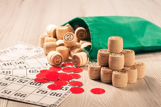 Loto de jeu de société. Barils de loto en bois avec sac vert, jetons rouges et cartes de jeu pour un jeu de loto