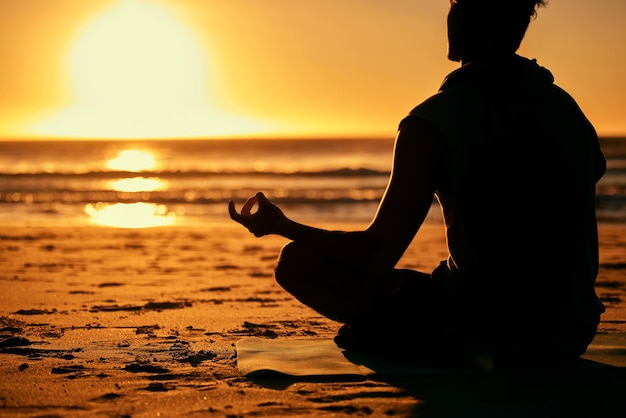 Lotus de méditation et silhouette d'homme à la plage à l'extérieur pour la santé et le bien-être Yoga zen au coucher du soleil et ombre ou contour d'un yogi masculin méditant la formation de chakra et l'exercice de pleine conscience au bord de la mer