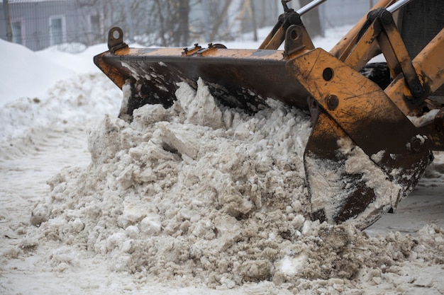 Louche de tracteur jaune enlevant la neige des rues de la ville. photo de haute qualité