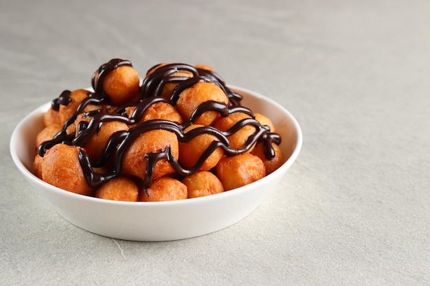 Loukoumades, luqaimat ou lokma avec garniture au chocolat dans une assiette blanche servie avec un thé