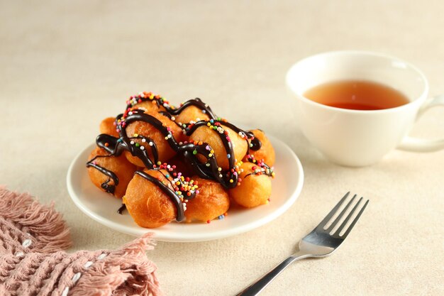 Loukoumades, luqaimat ou lokma avec garniture au chocolat et saupoudrage coloré dans une assiette blanche