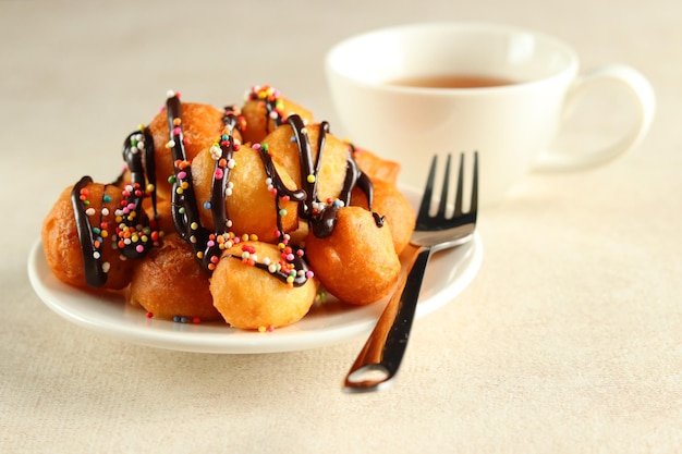 Loukoumades, luqaimat ou lokma avec garniture au chocolat et saupoudrage coloré dans une assiette blanche