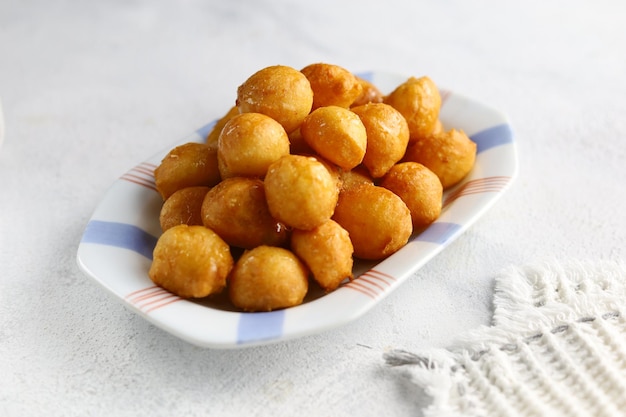 Loukoumades luqaimat ou lokma avec sauce au miel dans une assiette à fond blanc