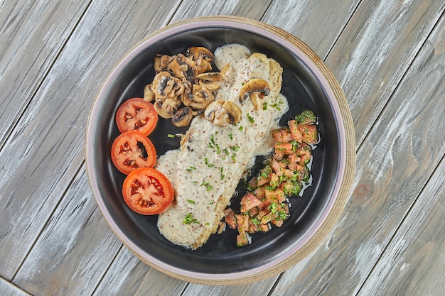 Loup de mer aux champignons moutarde et tomates sur plaque noire