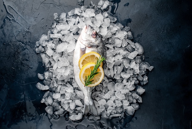 loup de mer cru réfrigéré et poisson dorado au citron et romarin sur glace, sur un fond de pierre