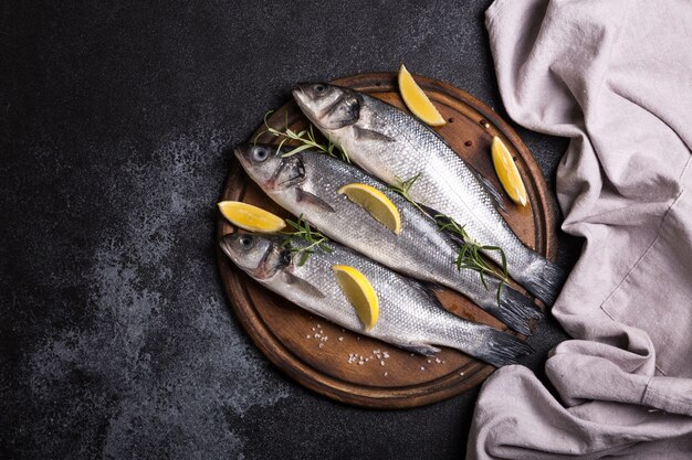 Loup de mer entier cru frais. Poisson cru au bar avec des épices et des herbes. Vue de dessus avec espace copie.