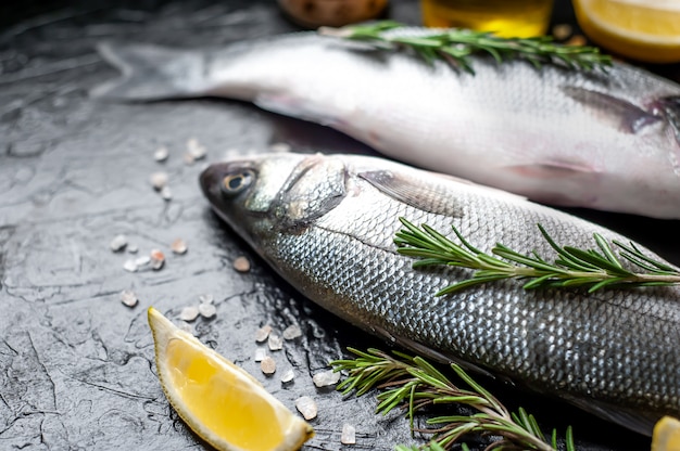 Loup de mer de poisson frais. Poisson de bar cru aux épices et herbes sur béton.