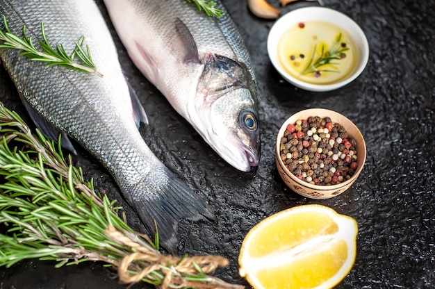 Loup de mer de poisson frais. Poisson de bar cru aux épices et herbes sur béton.