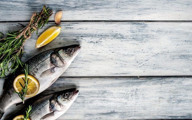 Loup de mer de poisson frais. Poisson cru au bar avec ingrédients épices et herbes sur fond de bois